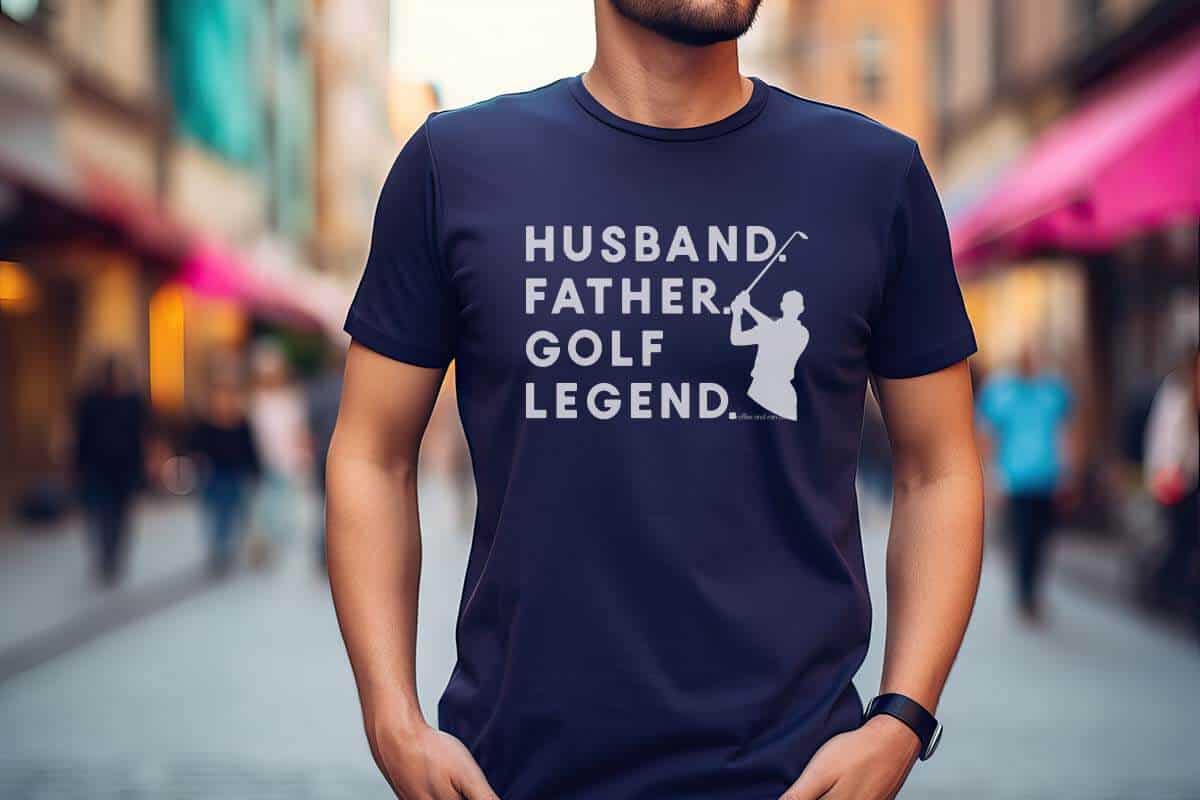 Horizontal image of a man on a street with a navy shirt which reads husband father golf legend with a golfer SVG silhouette.