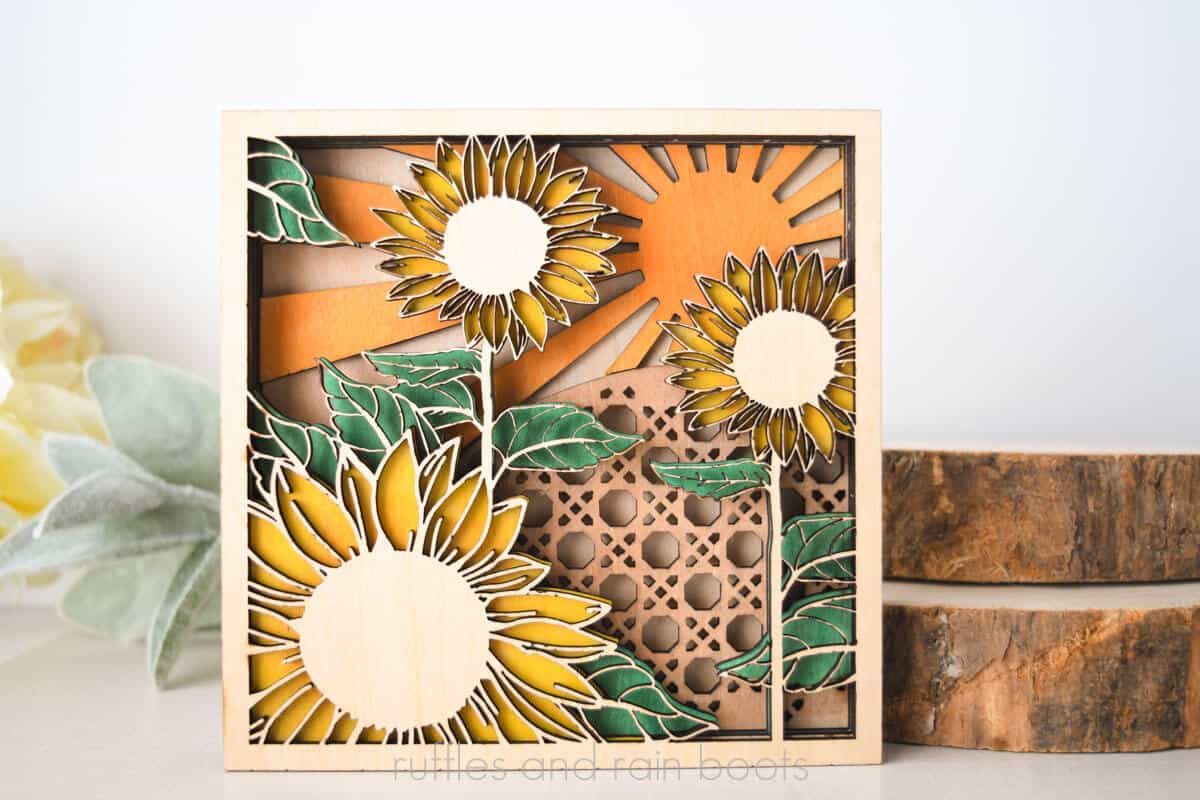 Horizontal image of a painted sunflower shelf sitter laser sign in wood, yellows, oranges, browns, and greens.