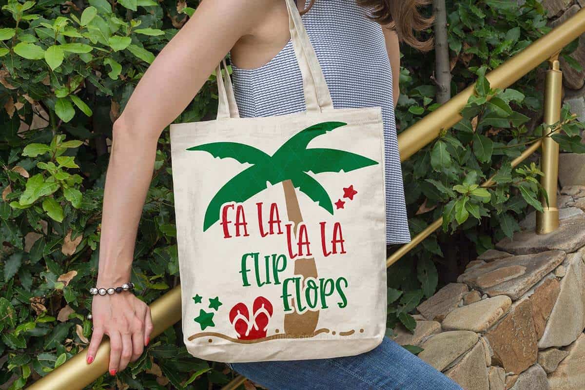 Horizontal image of a woman standing on stairs with a tote bag which reads fa la la la flip flops.