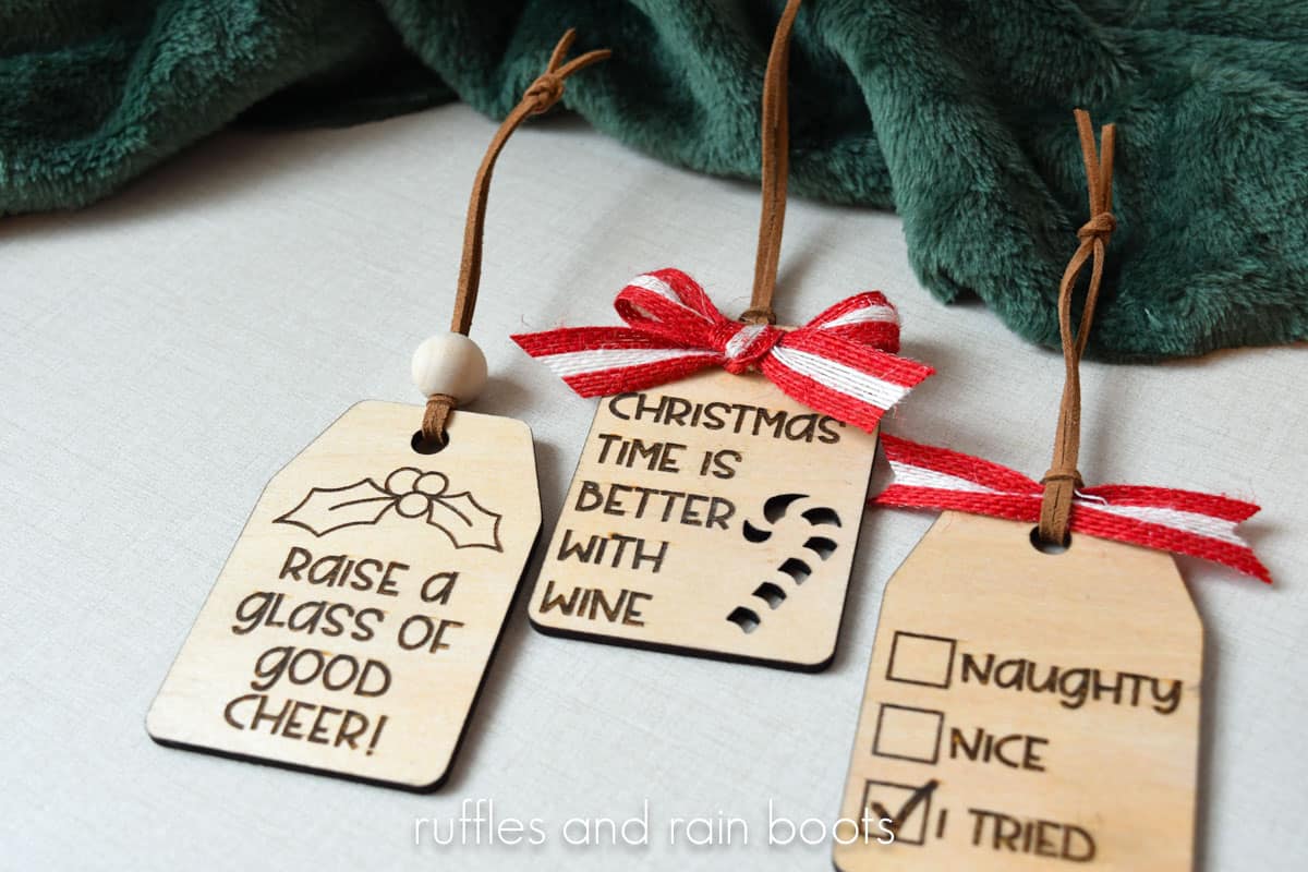Horizontal image of three laser engraved and laser cut wine tags for Christmas on a linen background.