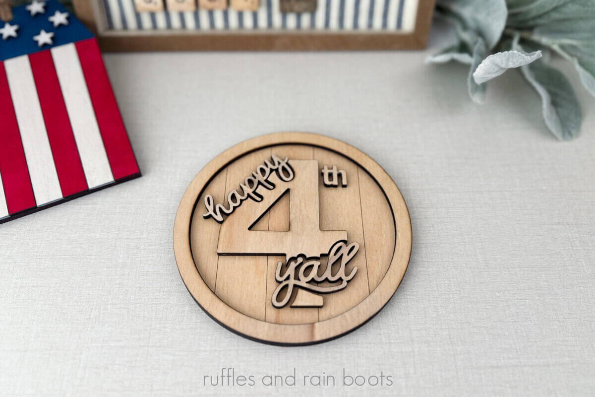 Horizontal image of a round wood sign that reads happy 4th Y'all.