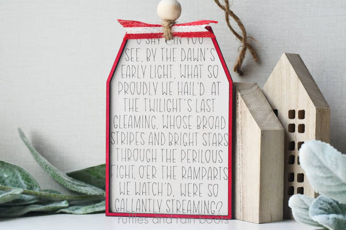 Horizontal image of a painted white, scored wood tag with a red frame for Independence Day decor.